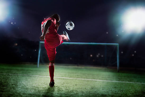 atleta rematar um bola de futebol em um golo - soccer night imagens e fotografias de stock