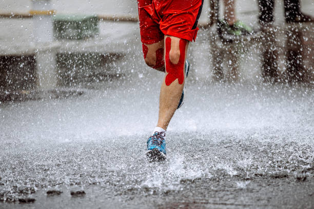 athlete runner knee kinesio tape running water splashes and drops stock photo