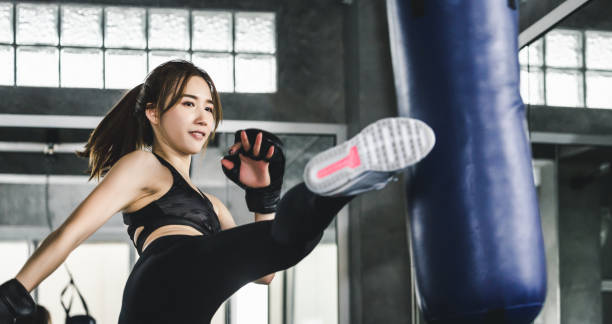 Athlete woman doing kick boxing training Young asian athlete fitness woman with boxing gloves doing kick boxing training in sport gym "martial arts" stock pictures, royalty-free photos & images