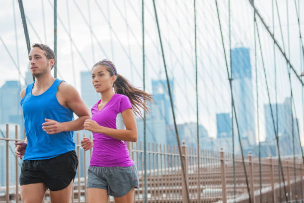 sportowcy biegacze biegający po moście brooklińskim w nowym jorku do treningu maratońskiego, trening fitness azjatyckiej kobiety i mężczyzny rasy kaukaskiej, pary międzyrasowej - brooklyn marathon zdjęcia i obrazy z banku zdjęć