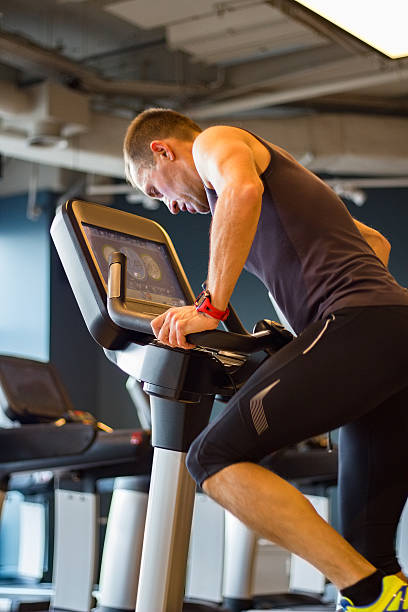 Athletic man cycling on stationary bike in gym stock photo
