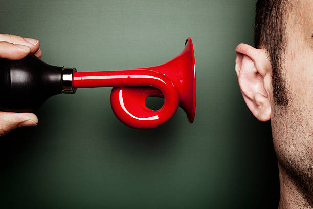 Attention Please - Signal Horn Ear Alarm Loud Scare Humor Conceptual photography. Somebody's holding a red signal horn very close to an ear. human ear stock pictures, royalty-free photos & images