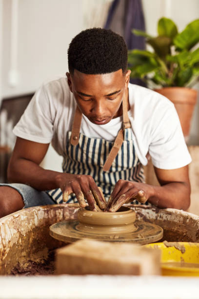 Attention to detail makes all the difference Shot of a young man working with clay in a pottery studio carving craft product stock pictures, royalty-free photos & images