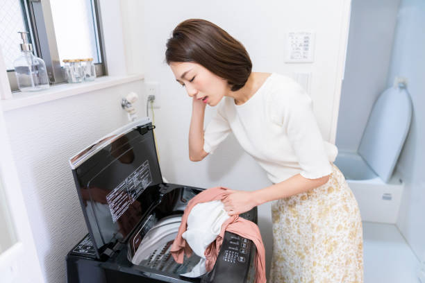 femme asiatique attrayante faisant la lessive, pensez - programmer machine à laver photos et images de collection