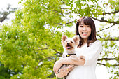 犬と公園でリラックスできる魅力的なアジア女性