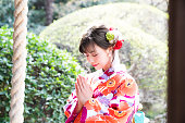 魅力的なアジア女性の神道神社で祈る日本の着物を着ています。
