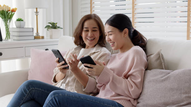 Attractive beautiful asian family sit sofa couch living room enjoy urban life joyful promotion discount shop buy health care insurance online quarantine activity isolate omnichannel experience at home stock photo