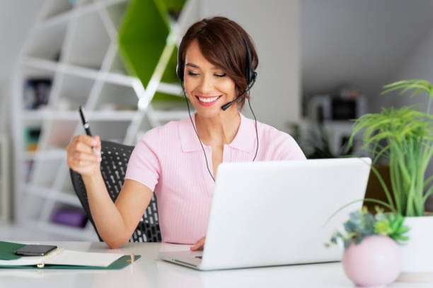 Attractive businesswoman having online meeting while sitting behind her laptop at office desk stock photo