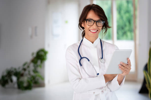 Attractive female doctor portrait while holding tablet in her hand and working at hospital stock photo