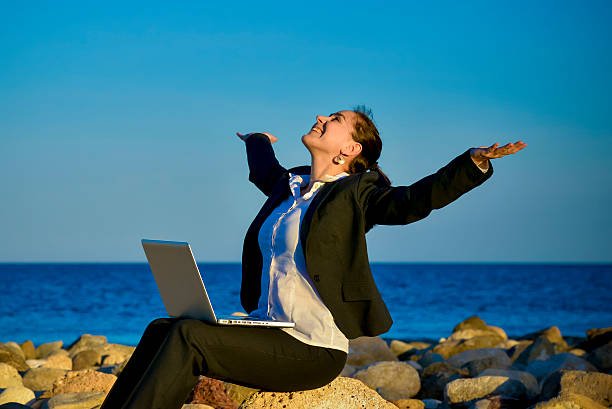 attractive business woman working on computer sitting on some rocks...