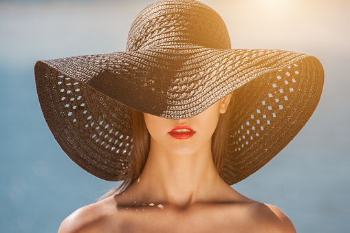 Attractive girl in a black hat worn on the head, on the beach