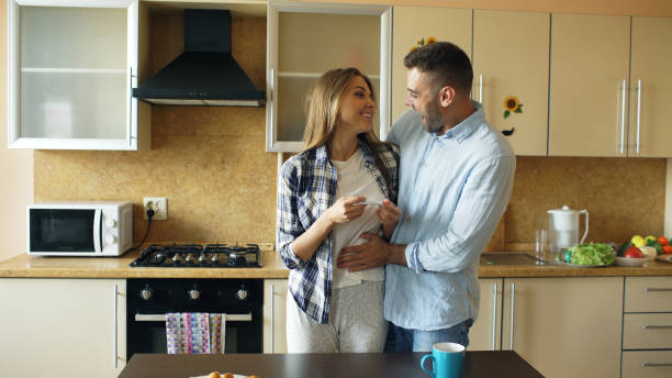 Attractive girl shows pregnancy test result to her boyfriend and surpise him at the kitchen stock photo