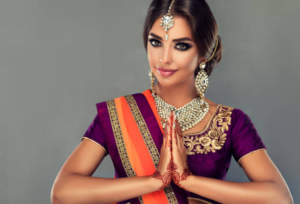 Attractive Indian woman is demonstrating welcome gesture-namaste. Oriental beauty. Perfect Indian woman is demonstrating welcome gesture. Portrait of beautiful indian girl dressed in a traditional national suit (sari), mehndi henna tattoo is painted on her hands and traditional kundan style jewelry set on her. namaste greeting stock pictures, royalty-free photos & images