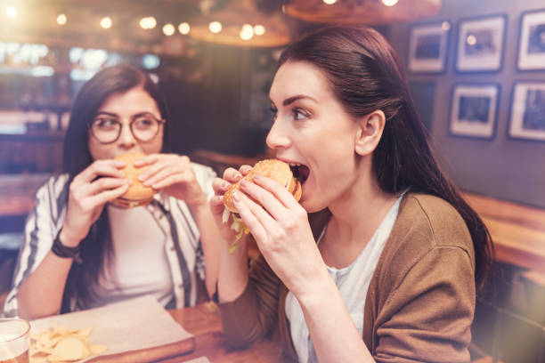 aantrekkelijke langharige vrouw haar hamburger eten - happy friday emoticon stockfoto's en -beelden