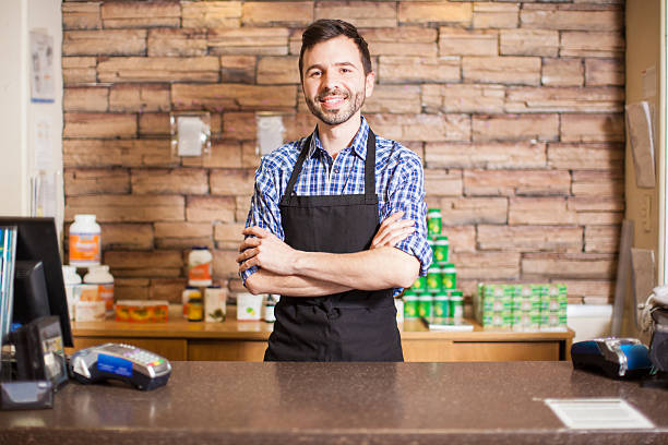 attractive male cashier in a grocery store - kas bouwwerk stockfoto's en -beelden