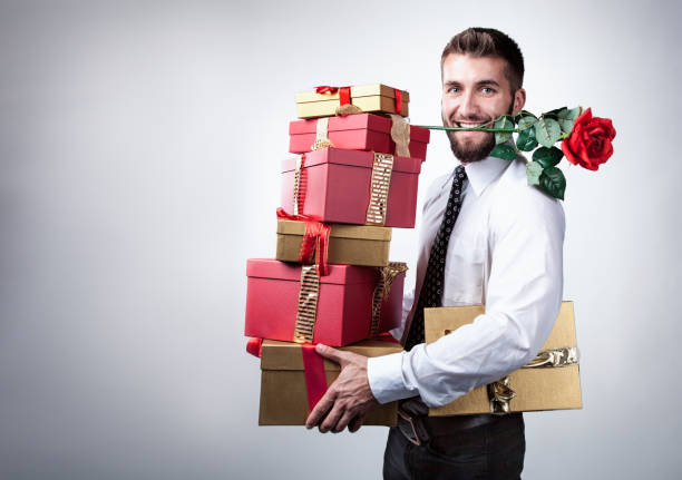 Attractive man with many presents and a rose in his mouth stock photo