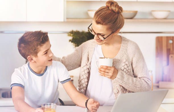 Attractive woman holding cup with tea Take a break. Delighted boy turning his head to his mom and expressing positivity while looking aside mother and teenage son stock pictures, royalty-free photos & images