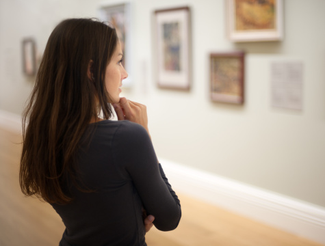 Beautiful woman thoughtfully looking at pictures in a private gallery. Nikon D3X. Converted from RAW. 