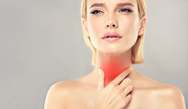 Attractive woman is touching the neck with expression of pain on the face. Sore throat and any type of inflammation. stock photo