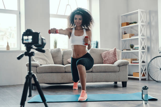 Attractive young African woman Attractive young African woman exercising using hand weight and smiling while making social media video influencer stock pictures, royalty-free photos & images