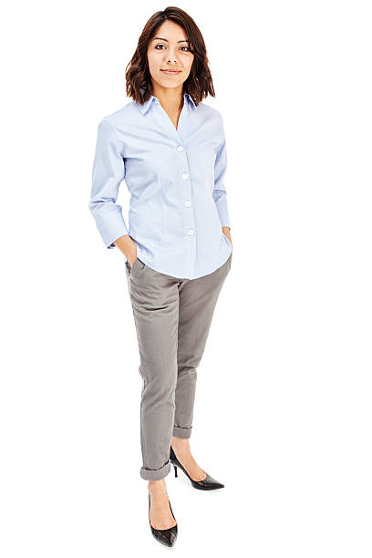 Attractive Young Hispanic Businesswoman Photo of an attractive young Hispanic businesswoman in blue button-down shirt, standing with hands in pockets; isolated on white. standing stock pictures, royalty-free photos & images