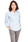 Photo of an attractive young Hispanic businesswoman in blue button-down shirt, standing with hands in pockets; isolated on white.