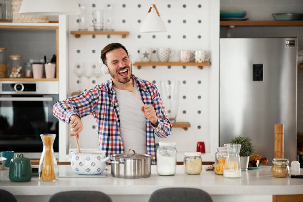 Attractive young man dancing and singing in the kitchen stock photo stock photo