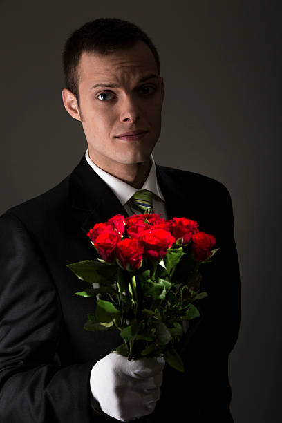 attractive young man with bouquet of roses in front of grey background