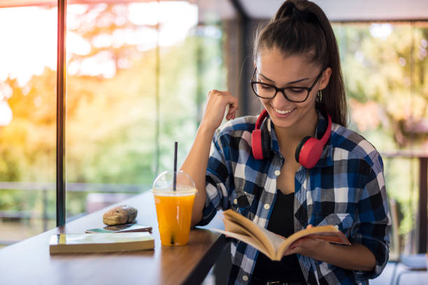 Attractive young woman reading a book in a cafe stock photo