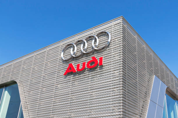 Audi sign against blue sky "Potsdam, Germany - September 16, 2012: Audi sign against blue sky. Beautiful red and silver Audi sign against blue sky. The sign was seen in Potsdam in front of an Audi dealership. Interesting is the modern facade of the audi building too. Typical for the audi logo are the four circles and the red color letters, the audi logotype." audi photos stock pictures, royalty-free photos & images