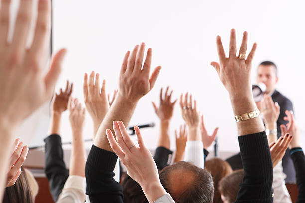 Audience raising hands in seminar or class room stock photo