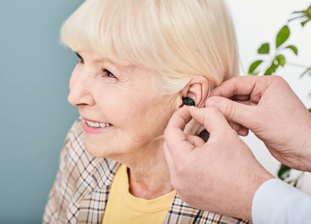聽力學家插入耳內助聽器給老年女病人，特寫。老年人聽力解決方案 - hearing aid 個照片及圖片檔