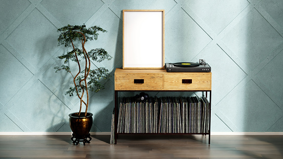 Audiophile room with empty poster frame mockup, green stucco wall with extruded shapes, large wood table for records, vinyl player, music records and a plant, rays of light from a window and shadows