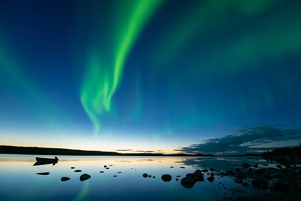 Aurora at Dusk Bands of curvy aurora borealis appear over a northern rocky lake right after sunset. boreal forest stock pictures, royalty-free photos & images