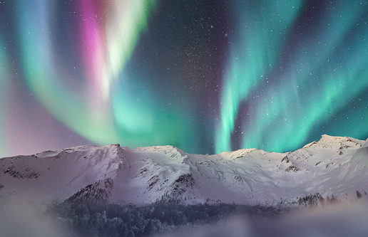 Aurora borealis over a snowy mountain range, fantasy landscape with snow and a starry sky with northern lights