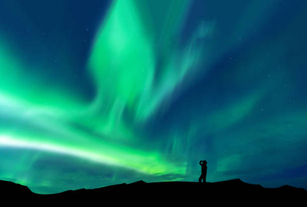 Aurora borealis with silhouette standing man on the mountain.Freedom traveller journey concept stock photo