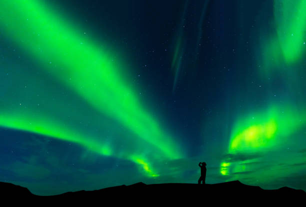 Aurora borealis with silhouette standing man on the mountain.Freedom traveller journey concept stock photo