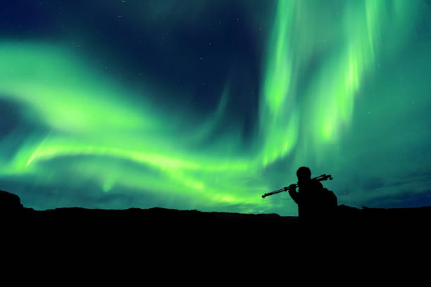 Aurora borealis with silhouette standing photographer on the mountain.Freedom traveller journey concept stock photo