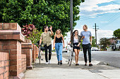 Four Australian friends walking in the street of Sydney on a sunny day.