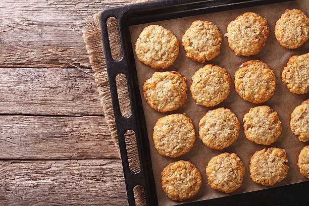 Australian oatmeal cookies on a baking sheet. Horizontal top view Australian oatmeal cookies close-up on a baking sheet on the table. horizontal view from above baking sheet stock pictures, royalty-free photos & images