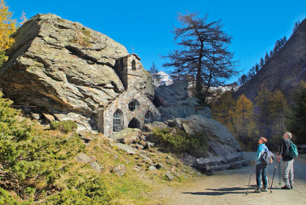 Austria, Osttirol, Rock Chapel Matrei, Austria - October 14, 2007: Two unidentified hikers on chapel named Felsenkapelle in Gschloesstal Valley , built into rock in East Tyrol near Matrei village, the valley is one of the most beautiful valleys in the Hohe Tauern national park in the Austrian Alps and a popular hiking area osttirol stock pictures, royalty-free photos & images