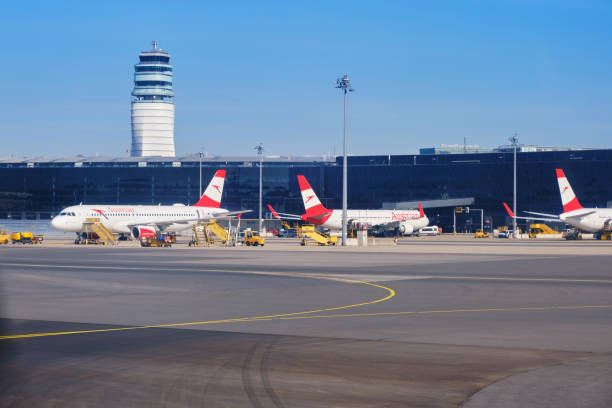 Austrian Airlines planes on the ground at Vienna International Airport (VIE), with control tower in the back and clear blue skies. stock photo