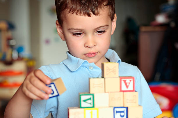 Autistic boy building with blocks Child with autism deciding where is the best place to put his block. Shall he build it higher? autism stock pictures, royalty-free photos & images