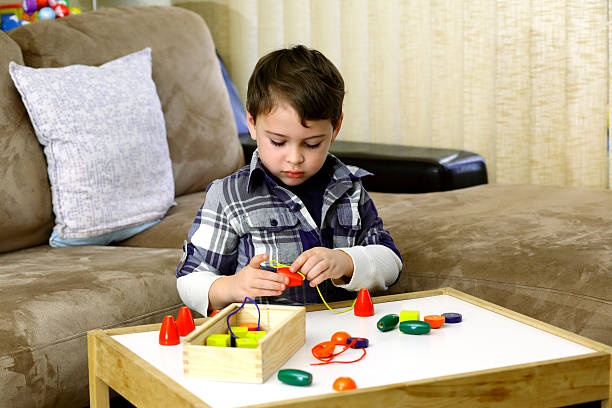 Autistic boy playing with colorful wooden beads stock photo