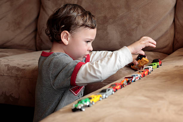 Autistic boy playing with toy cars stock photo