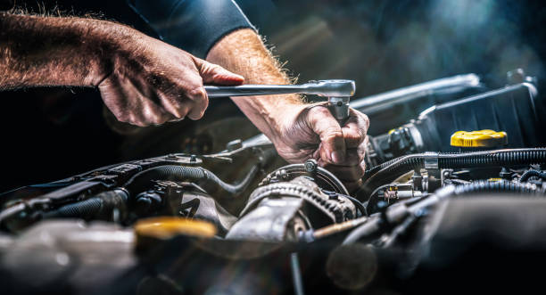 automonteur die aan automotor in werktuigkundige garage werkt. reparatieservice. authentieke close-up shot - car stockfoto's en -beelden