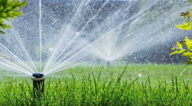 automatische sprinklerinstallatie drenken van het gazon op een achtergrond van groen gras - irrigatiesysteem stockfoto's en -beelden