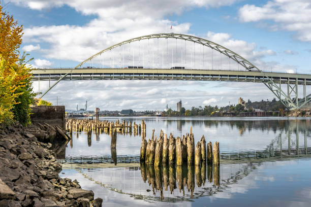 Automotive double-story arched Fremont Bridge over the Willamette River in Portland with water reflection and remnants of the piles of the old pier stock photo