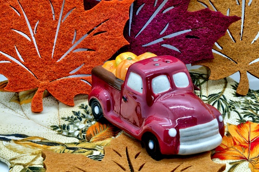 close up ohoto of salt pepper shaker in the form of an old pickup trudk with pumpkins and thanksgiving decorations