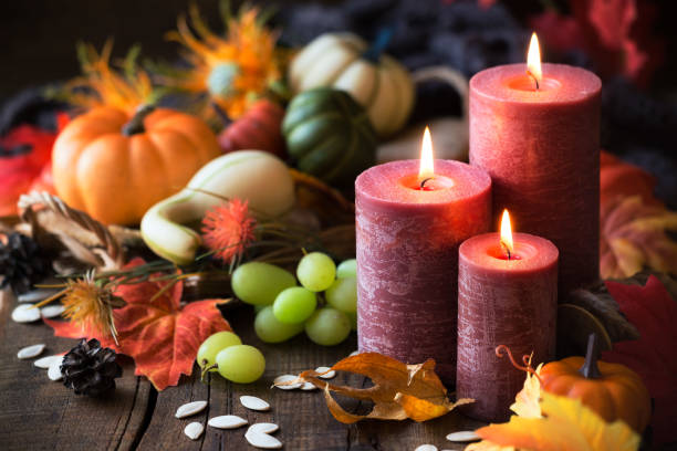 Thanksgiving dinner concept. Lit candles with pumpkins, grapes,...